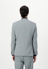 Szary żakiet w slim fit, z pojedynczym rozcięciem z tyłu i bocznymi kieszeniami. Posiada subtelną teksturę oraz czarne akcenty na kołnierzu.