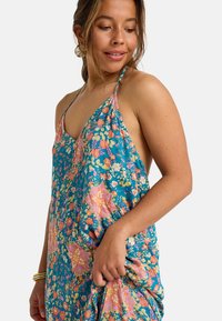 Bloemen maxi-jurk met een turquoise basis, met roze en oranje patronen. Bandjes vormen een halternek, lichtgewicht stof met een vloeiende silhouet.