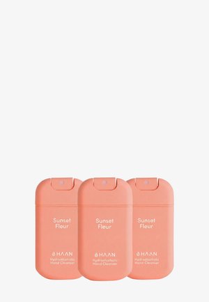 Tre koralfarvede HAAN Sunset Fleur hydroalkoholiske håndrensflasker med flip-top spray låg.
