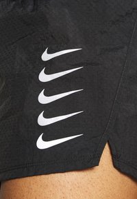 Black athletic shorts featuring a textured fabric, with five white Nike swoosh logos displayed in a vertical pattern on the side.