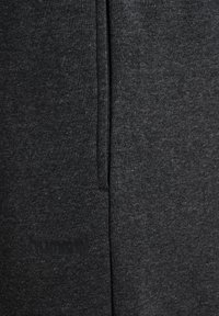 Charcoal grijze joggingsbroek van zacht, textuurstof. Voorzien van een elastische tailleband en zijzakken. Geëmbossed logo nabij het onderste deel van het linkerbeen.