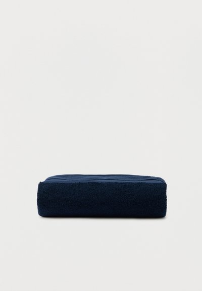 Dark blue folded towel lying flat on a light background, showing its thickness and texture.
