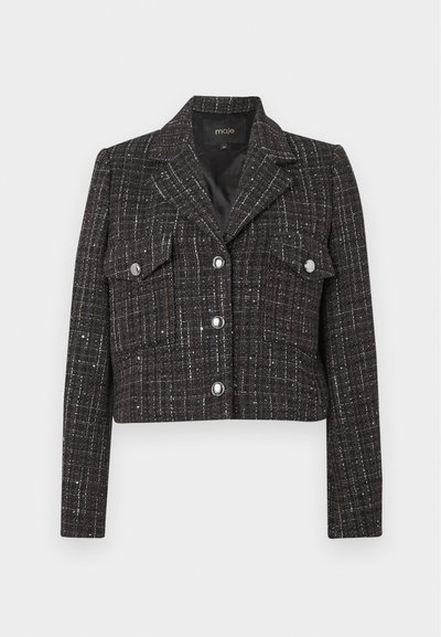 Lyhyt musta tweed-takki, jossa on hopealankaa, läpällinen kaulus, kaksi rintataskua ja nappikiinnitys. Sujuva vuori ja istuva malli.