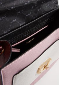 Strukturalna torebka w kolorze białym i różowym, wykonana z teksturowanego materiału syntetycznego, wyposażona w zapięcie w złotym odcieniu, kieszeń na zamek oraz wewnętrzną podszewkę z logo marki.