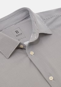 Camicia a maniche corte con fantasia a scacchi bianco e nero, realizzata in cotone. Presenta un colletto a punte e bottoni bianchi, con una texture liscia.