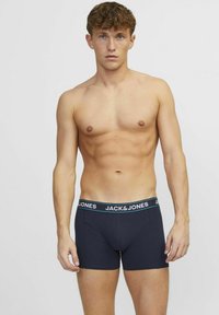 Boxers ajustados de color azul oscuro con una cinturilla negra que presenta el texto "JACK&JONES" en blanco. Textura suave, diseño ajustado y longitud hasta la mitad del muslo.