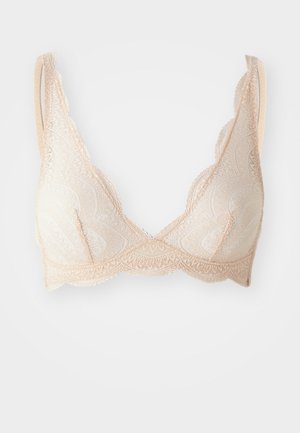 Brassière en dentelle beige clair avec des bonnets en triangle, des bords festonnés et des bretelles ajustables. Présente des motifs complexes et une texture douce.