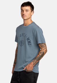 Hellblaues Baumwoll-T-Shirt mit Rundhalsausschnitt, kurzen Ärmeln und einem bedruckten Logo auf der Vorderseite. Mit feinen Nähdetails.