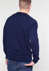 Sudadera azul marino de manga larga, con puños y dobladillo de canalé. Presenta un cuello redondo y un diseño de punto texturizado. Se muestra vista trasera.
