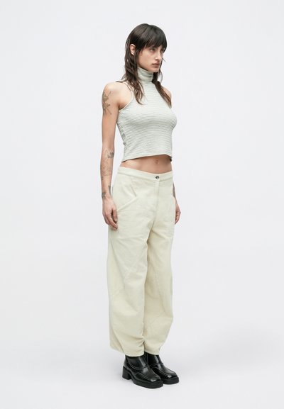 Γκρι ριγέ αμάνικο τοπ με ψεύτικο λαιμό, συνδυασμένο με κρεμ φαρδιά παντελόνια από κορδούρα και μαύρα μποτάκια με πλατφόρμα. Ομαλή υφή, άνετη γραμμή.