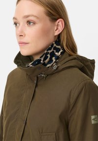 Olijfgroene jas met capuchon, voorzien van een voering met luipaardprint. Voorkant met drukknoopsluiting, twee zijzakken en merkdetail op de mouw.