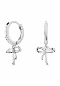 Srebrne kolczyki w kształcie kół z delikatnym urokiem w kształcie kokardy, gładkim wykończeniem i wypolerowaną fakturą. Projekt jest elegancki i minimalistyczny.