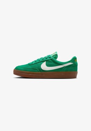 Grønne semskede joggesko med hvit swoosh og teksturert overflate. Har en gummisåle og gul branding på hælen. Snøresystem.