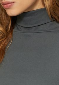 Pull à col roulé gris en tissu lisse et extensible avec texture côtelée, présentant un col haut et une coupe ajustée.