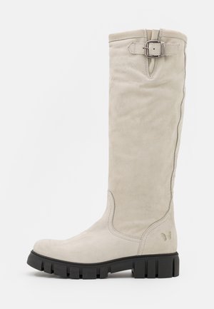 Botte haute en suède grise claire avec semelle épaisse noire et sangle en boucle argentée près du haut.