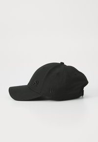 Sort baseball cap med en rund krone og buet skygge. Har prægede logoer foran og på siden, lavet af tekstureret stof.