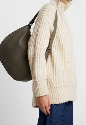 Un doux pull en tricot beige avec une texture côtelée, associé à un sac à main en cuir vert foncé lisse, de forme arrondie et avec une bandoulière robuste.