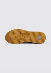 Suela de zapatilla de goma con surcos texturizados y la inscripción "WALK IN PITAS" en relieve, con un contraste de colores marrón y beige.
