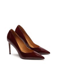 Pár lesklých tmavočervených lodičiek s špicatou špičkou a béžovým vnútorným podšitím na bielom pozadí.