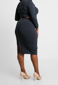 Pruhovaný dvoudílný set v námořnické modři a olivové barvě, s přiléhavým střihem, dlouhými rukávy a zadním zipem se štěrbinou na sukni.
