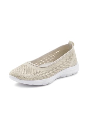 Beige knitted slip-on shoe with a textured upper and perforated design. White flexible sole, rounded toe, and pull tab at the heel.