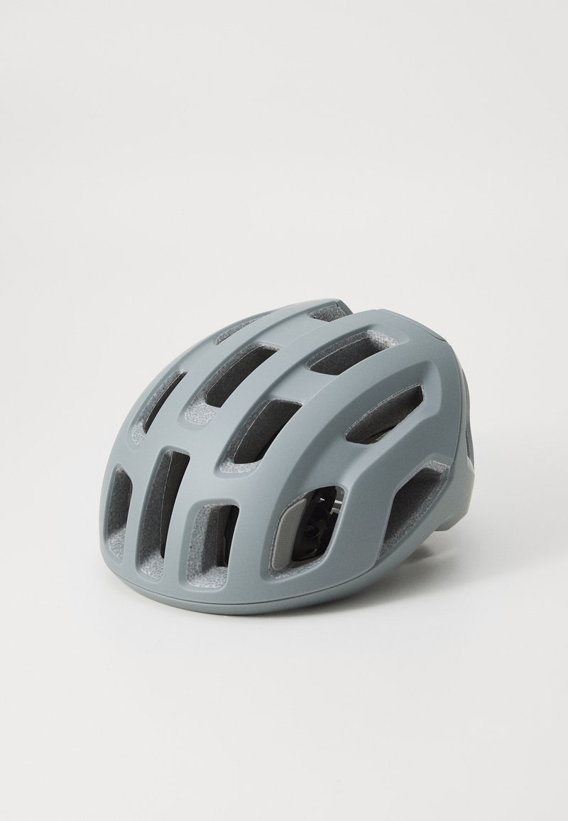 Szary kask rowerowy o opływowym kształcie, z wieloma otworami wentylacyjnymi i matowym wykończeniem. Zawiera regulowane paski wewnętrzne.