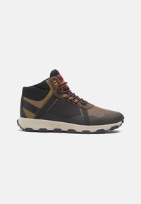 Mid-top hiking shoes featuring a mix of brown, black, and tan materials, mesh panels, red laces, and a textured rubber sole.