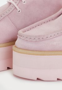 Ροζ σουέτ παπούτσια με στρογγυλή μύτη, διαθέ�τουν ραφές σε απόχρωση του υλικού και χοντρή πλατφόρμα. Η υφή φαίνεται απαλή και λεία.