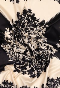 Tissu à motif floral noir et crème, présentant une texture lisse et un drapé élégant, avec des détails complexes et des accents de bordure contrastants.