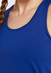 Blauw mouwloos sport tanktop met een ronde halslijn en een gladde textuur, ontworpen voor comfort en gemakkelijke beweging.