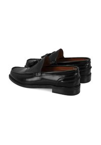 Zwarte leren loafers met een verhoogd naaddesign, decoratieve kwastjes en een platte rubberen zool. Glad oppervlak met een gepolijste afwerking.