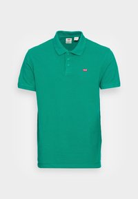 Zielona koszulka polo wykonana z bawełny, z kołnierzykiem, trzema guzikami i małym czerwonym logo Levi's na górnej lewej części klatki piersiowej.