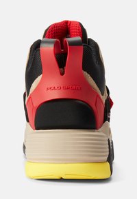 Back view of a multicolored Polo Sport sneaker with red heel support, beige midsole, black upper, and yellow outsole.