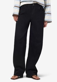 Μαύρα παντελόνια με φαρδιά πόδια, από τζιν υλικό, ψηλόμεσο σχέδιο, μπροστινές τσέπες, διακριτές ραφές, συνδυασμένα με ένα ριγέ τοπ και σαγιονάρες.