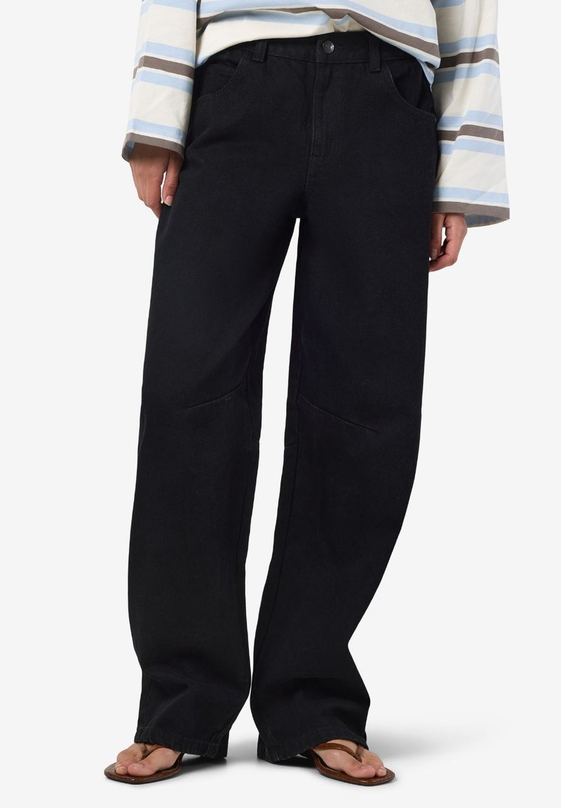 Μαύρα παντελόνια με φαρδιά πόδια, από τζιν υλικό, ψηλόμεσο σχέδιο, μπροστινές τσέπες, διακριτές ραφές, συνδυασμένα με ένα ριγέ τοπ και σαγιονάρες.