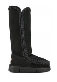 Stivale alto in suede nero con un bordo texturizzato lungo la cucitura, caratterizzato da una suola piatta in gomma e un'etichetta con il marchio sul tallone.