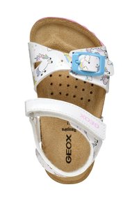 Sandalias blancas con un patrón de unicornios y estrellas, hebilla azul ajustable, plantilla de corcho y tira blanca con el logo "GEOX".