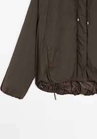 Braune gesteppte Jacke mit elastischen Bündchen, vorderen Seitentaschen, Kordelzug am Saum und einem verdeckten Frontreißverschluss.