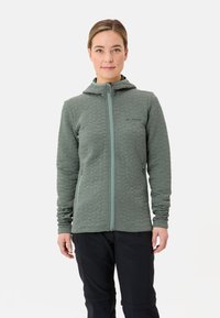 Gequilte groene fleecjas met een capuchon, frontale rits en twee zijzakken. Bevat een textuurpatroon en een contrasterende ritskleur.