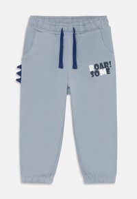 Pantalons de survêtement bleu clair pour tout-petits avec taille élastique et poignets, cordons de serrage bleu marine, pics de dinosaure sur les côtés et graphique "ROAR! SOME" sur la jambe droite.