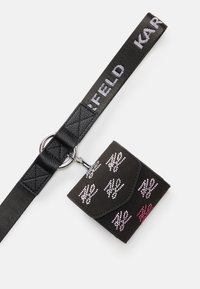 Black wallet with pink and silver studded patterns attached to a black fabric strap with white text and metal ring.