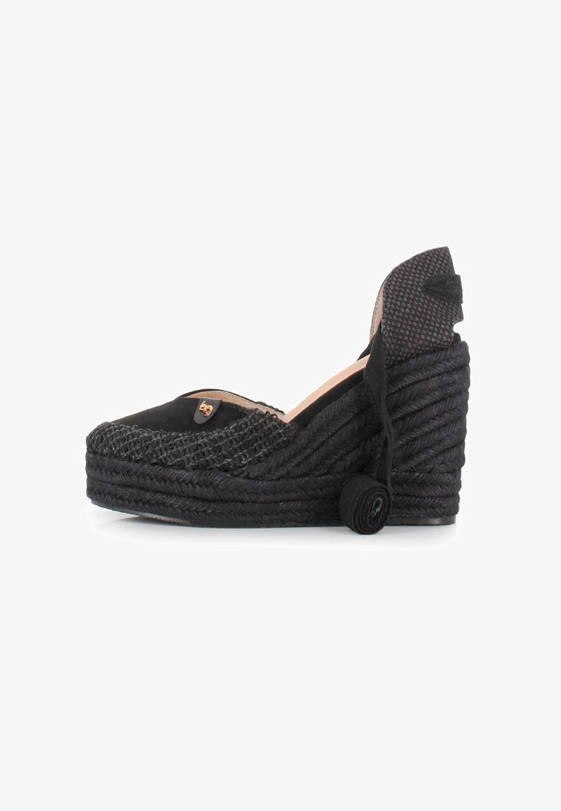 Espadrille de cuña negra con detalles de yute trenzado, punta redonda y tacón cubierto de tela. Presenta un emblema decorativo en la parte delantera.