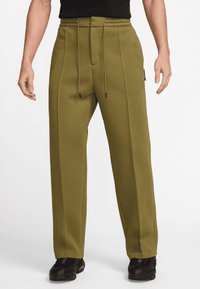 Olivgröna byxor med vida ben i mjukt tyg, med dragsko i midjan, synliga sömmar och två sidofickor.