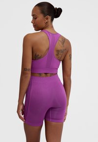 Fioletowy sportowy crop top i szorty z wysokim stanem, z designem na plecach, prążkowaną strukturą i oddychającymi akcentami z siateczki.