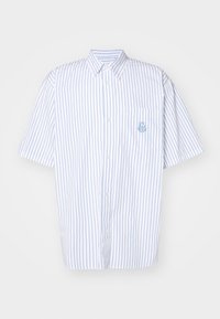 Lyhythihainen nappikauluspaita valkoisesta puuvillasta, jossa siniset pystysuorat raidat. Vasemmassa rintataskussa ja kirjailtu logoyksityiskohta.