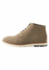 Stivaletto in suede tan con punta rotonda, design con lacci, suola bianca a contrasto e dettagli marroni lungo il midsole.