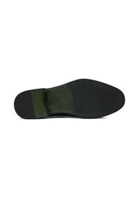 Black rubber sole with a smooth finish, featuring a green leather patch near the heel, and visible stitching along the edge.