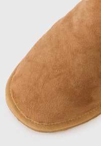 Rjavi semiš čevlji z zaobljenim nosom, mehkobo in šivanim robom. Podplat je lahek z gladko površino.