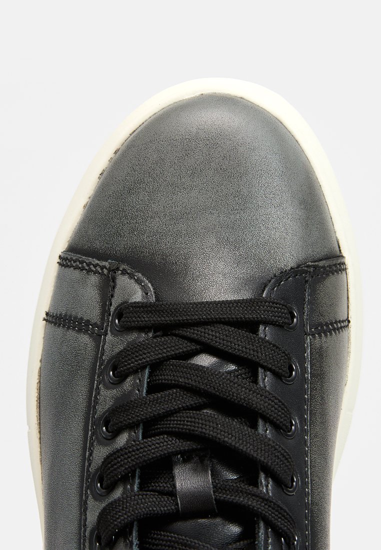 Sneaker in pelle nera con finitura liscia, dotato di lacci neri, dettagli di cucitura e suola in gomma bianca. Design della punta arrotondata.