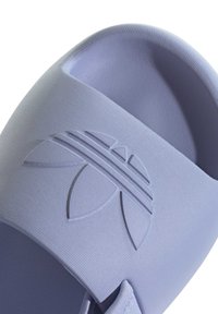 Světlofialové nazouvací sandály s texturovaným povrchem, s vyvýšeným logem listu a horizontálními pruhy na horním pásku.